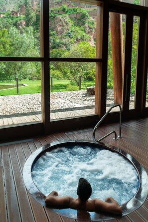 A hot tub with a view of a mountainous landscape through large windows.