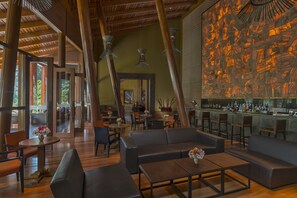 A spacious lounge area with leather seating, wooden tables, and a large abstract mural on the wall.