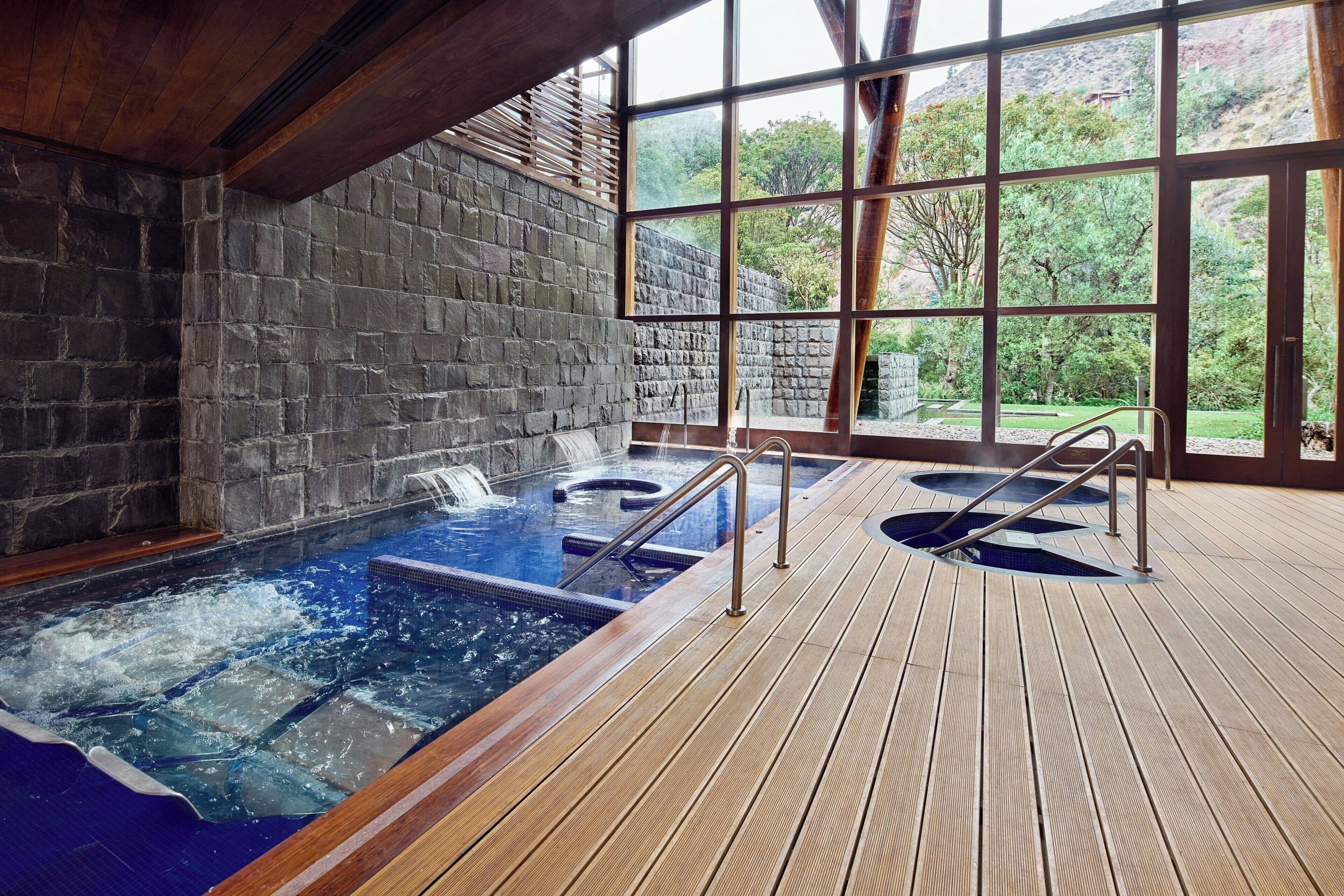 A hot tub area with a wooden deck and stone walls.