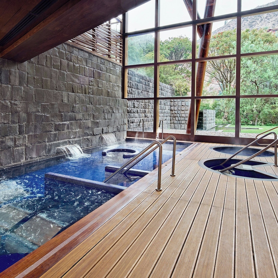 A hot tub area with a wooden deck and stone walls.