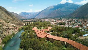 Un paisaje montañoso con un río, un pueblo y un edificio de techo rojo.