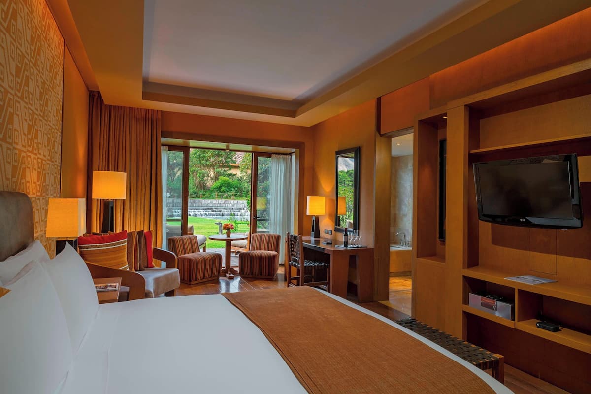 A hotel room with a large bed, a desk, a TV, and a view of the outdoors.