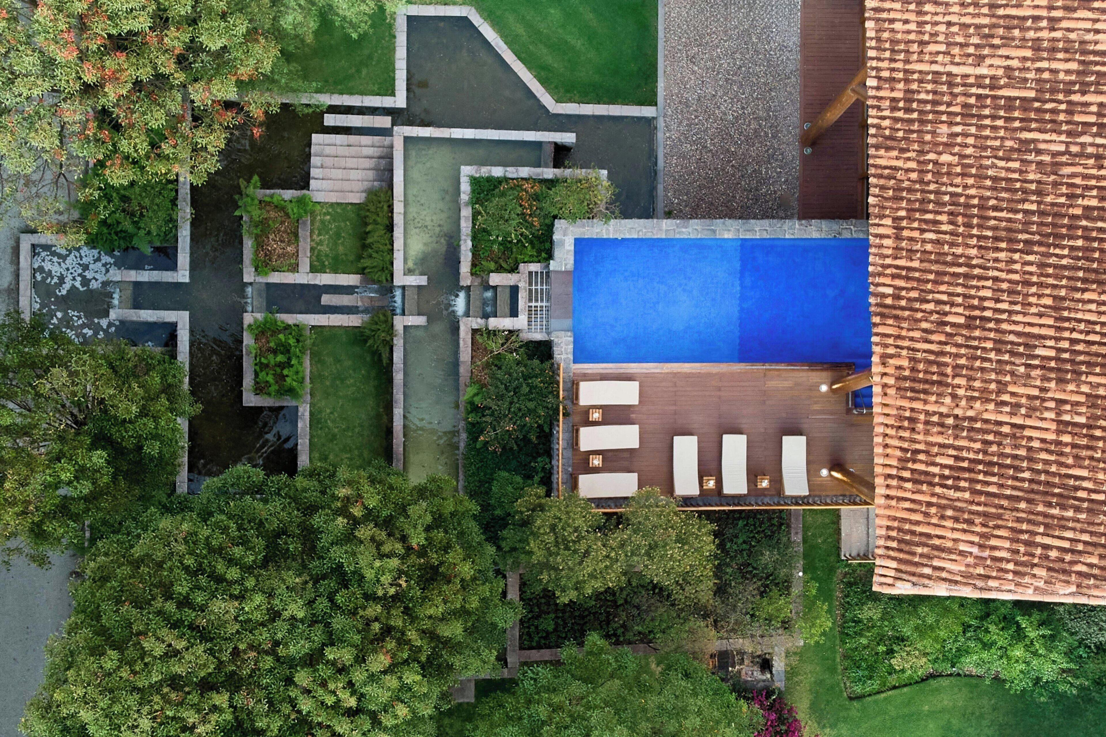 An aerial view of a property with a swimming pool, outdoor seating area, and landscaped garden.