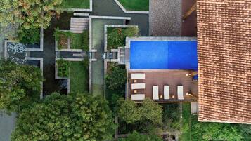An aerial view of a property with a swimming pool, outdoor seating area, and landscaped garden.