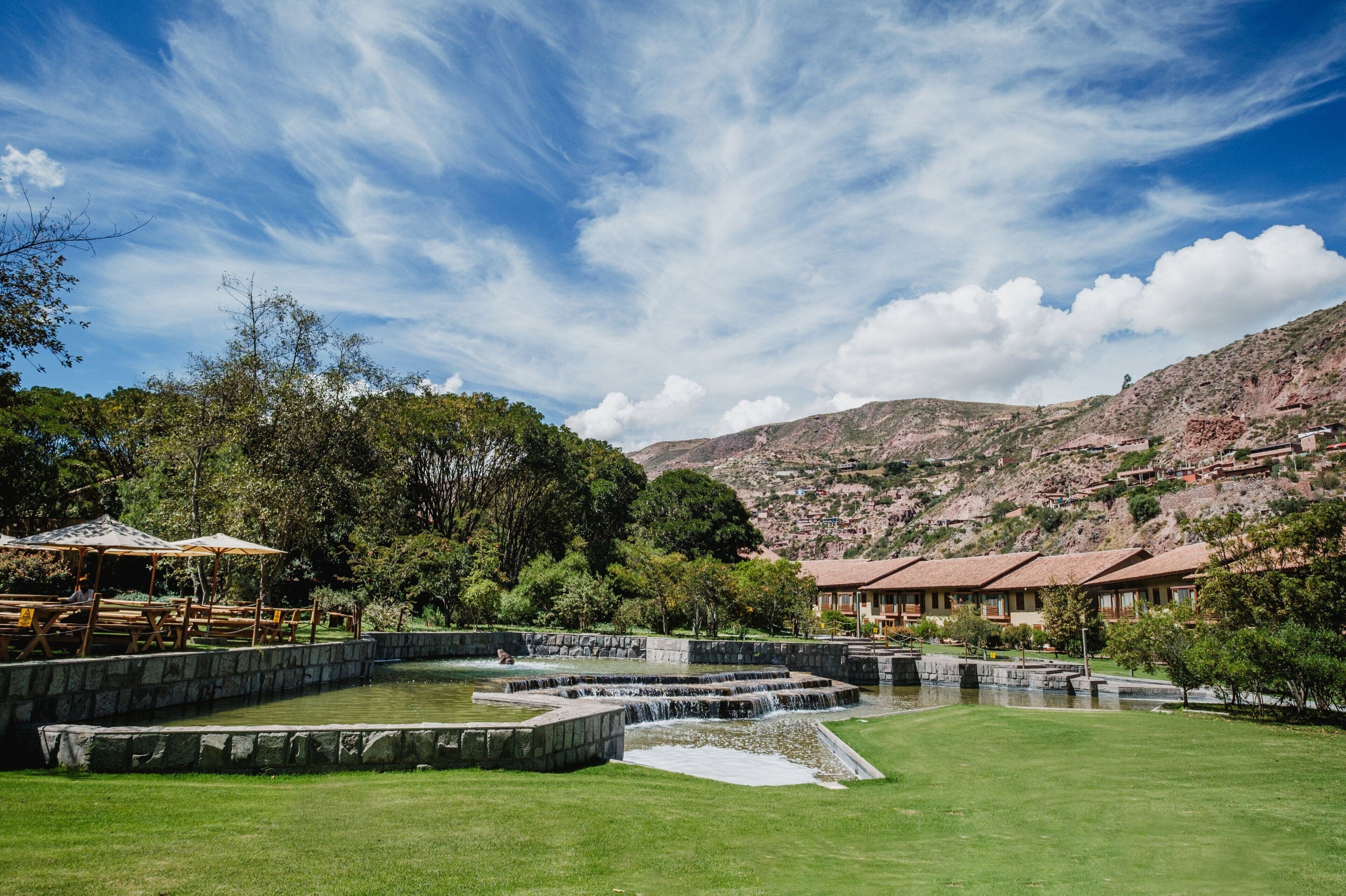 A hotel with a pool area, outdoor seating, and a mountainous backdrop.