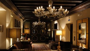 Un vestíbulo de hotel con candelabro, zona de estar y mostrador de recepción.