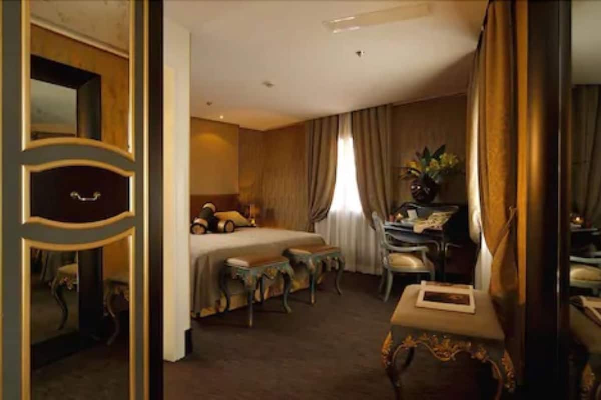 A hotel room with a bed, a desk, a chair, and a small table.