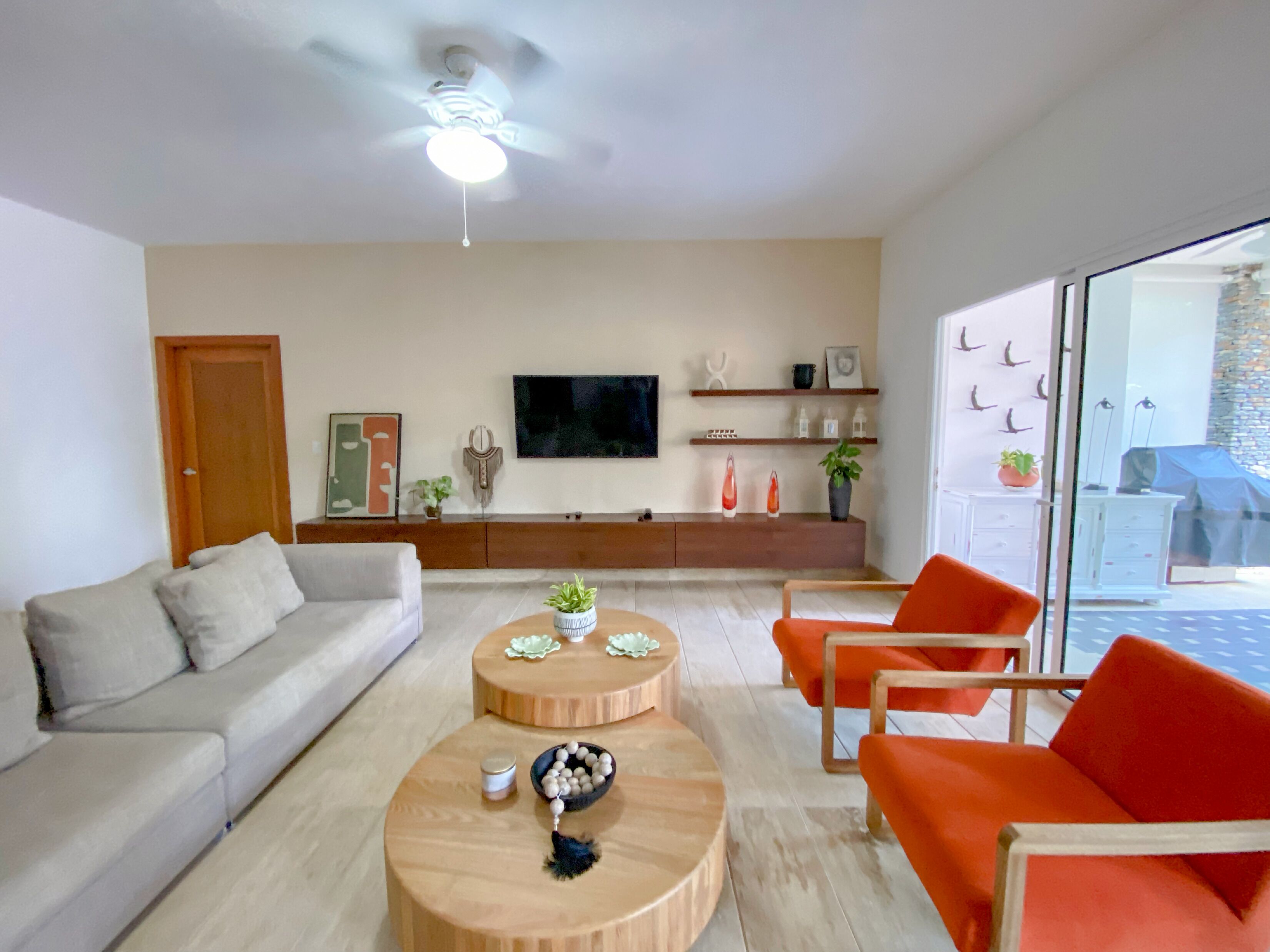 Una sala de estar moderna con un sofá, dos sillones, una mesa de centro y un televisor en la pared.