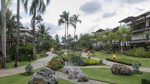 Un resort con un camino central, palmeras y un jardín bien cuidado.