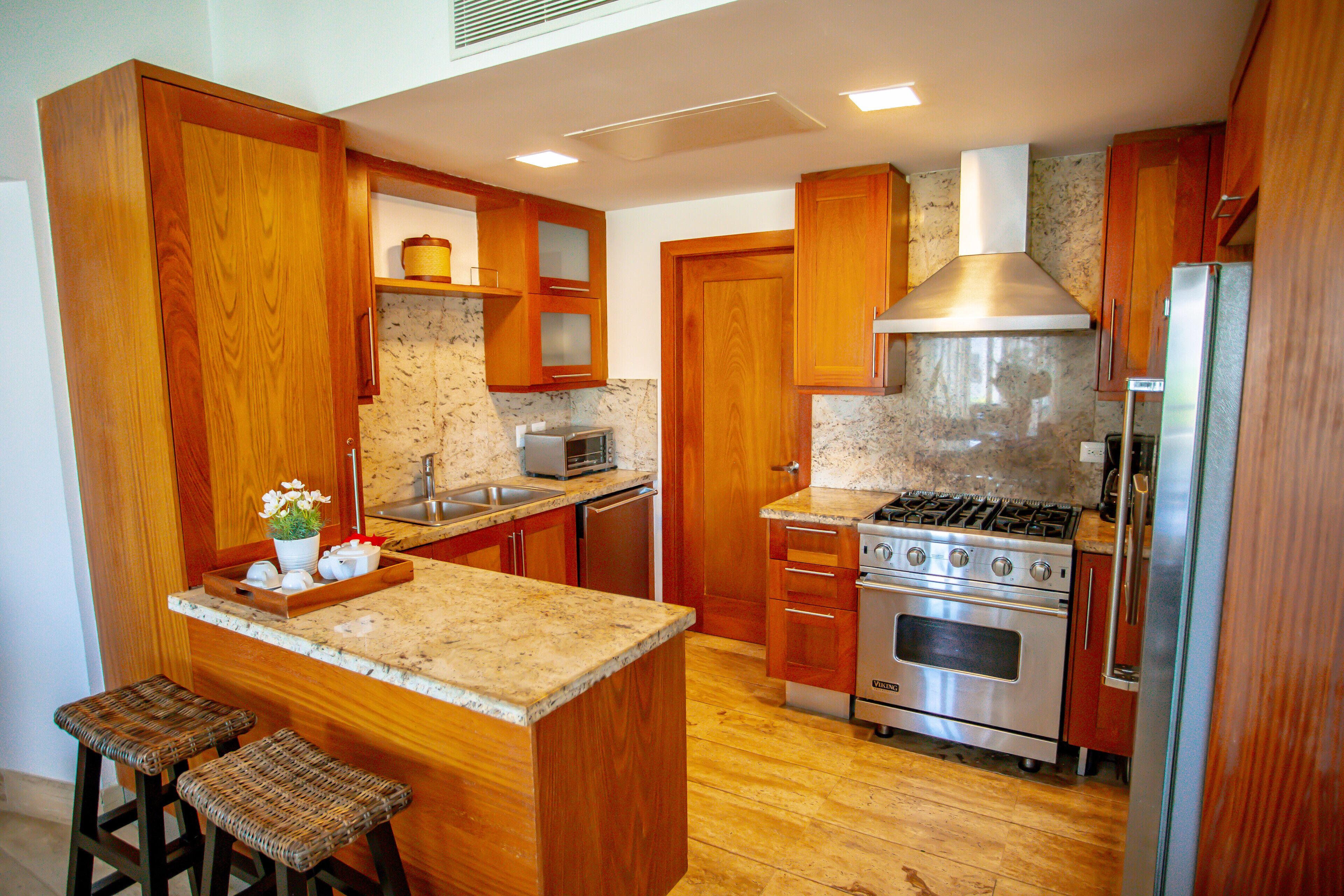 A kitchen with wooden cabinets, a granite countertop, a stainless steel stove, and a microwave.