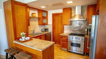 A kitchen with wooden cabinets, a granite countertop, a stainless steel stove, and a microwave.