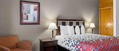 Een hotelkamer met een bed, twee nachtkastjes met lampen, een stoel en een houten garderobe.