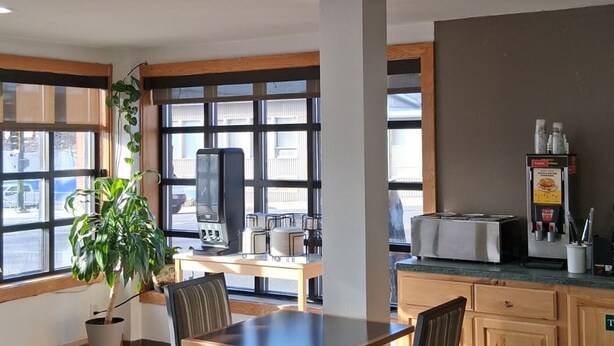 Une cuisine moderne avec un coin repas, de grandes fenêtres et une plante en pot.