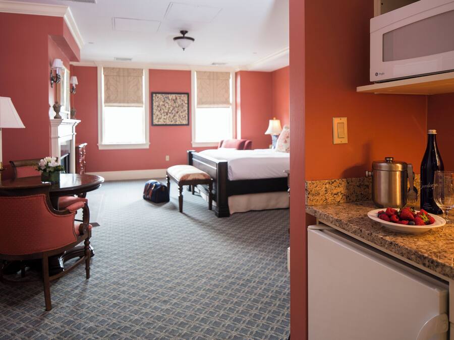 Une chambre d’hôtel comprenant un lit, un bureau avec une chaise, une table à manger et un coin cuisine équipé d’un four à micro-ondes.