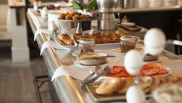 Un buffet proposant une variété de plats, notamment des pâtisseries, des fruits et des condiments.