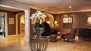 A lobby with a central ornamental table, seating area, and a framed picture on the wall. - Delamar Southport (Southport)