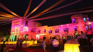 A historic building with arched windows and a tower, decorated with string lights. - The Fort Ramgarh (Panchkula)