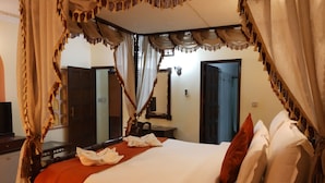 A hotel room with a four-poster bed, a television, and a mirror. - The Fort Ramgarh (Panchkula)