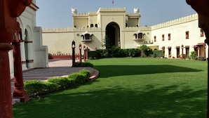 A courtyard with a large building in the background, featuring a central archway and a flag on top. - The Fort Ramgarh (Panchkula)