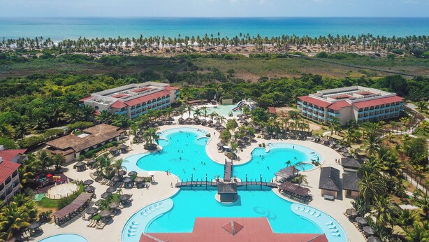 Un resort con piscina central, varias edificaciones para huéspedes y una zona de playa.