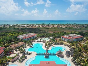 Un complexe hôtelier doté d’une piscine centrale, de plusieurs bâtiments abritant les chambres et d’une zone de plage.