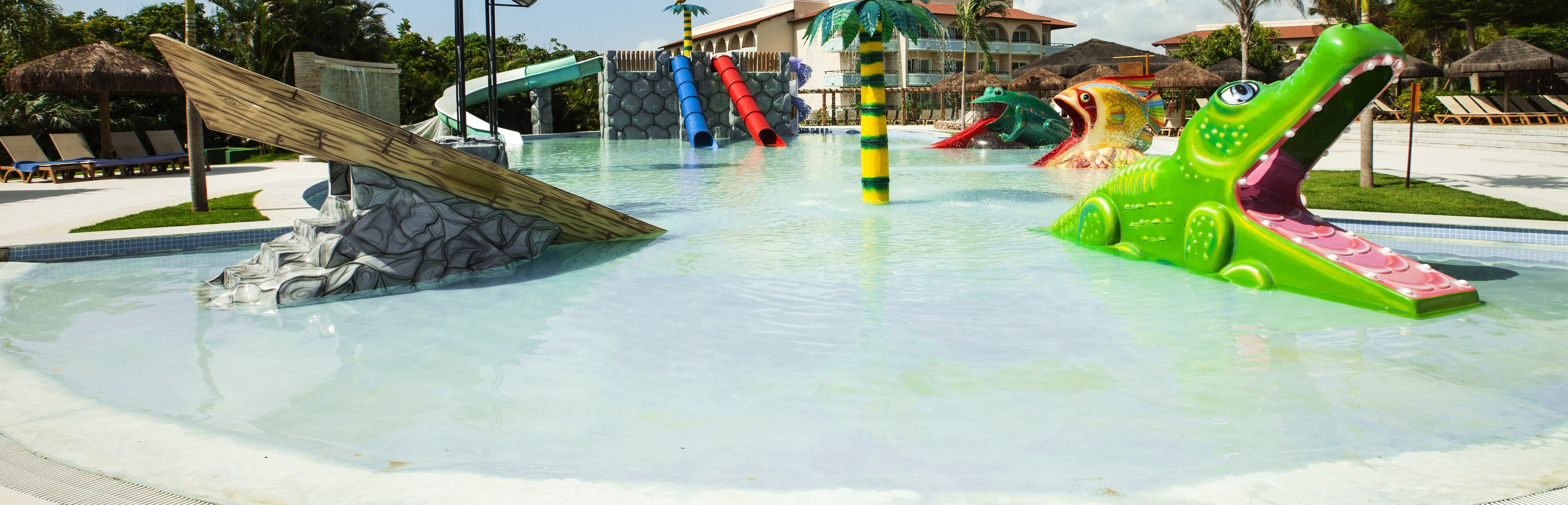 Un parco acquatico con scivoli, incluso uno scivolo a forma di coccodrillo verde gigante.