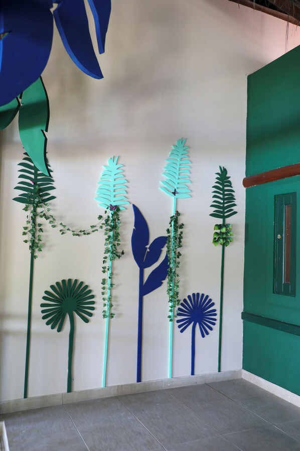A room with a green wall and a white ceiling. There are decorative paper cutouts of leaves and flowers on the wall.