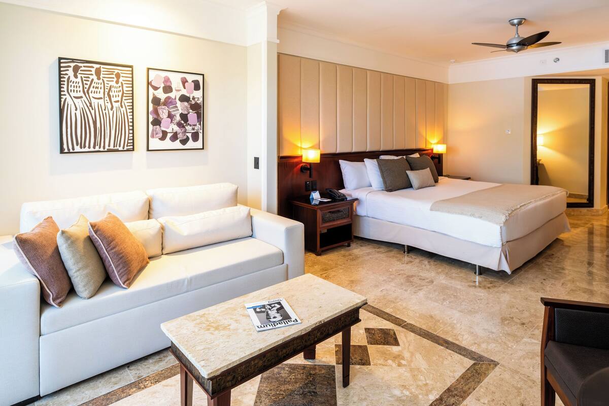 Una habitación de hotel con cama, sofá, mesa de centro y obras de arte en las paredes.