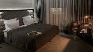Ein modernes Hotelzimmer mit einem großen Bett, einem Nachttisch, einem Sessel und einem Schreibtisch mit einer Lampe.