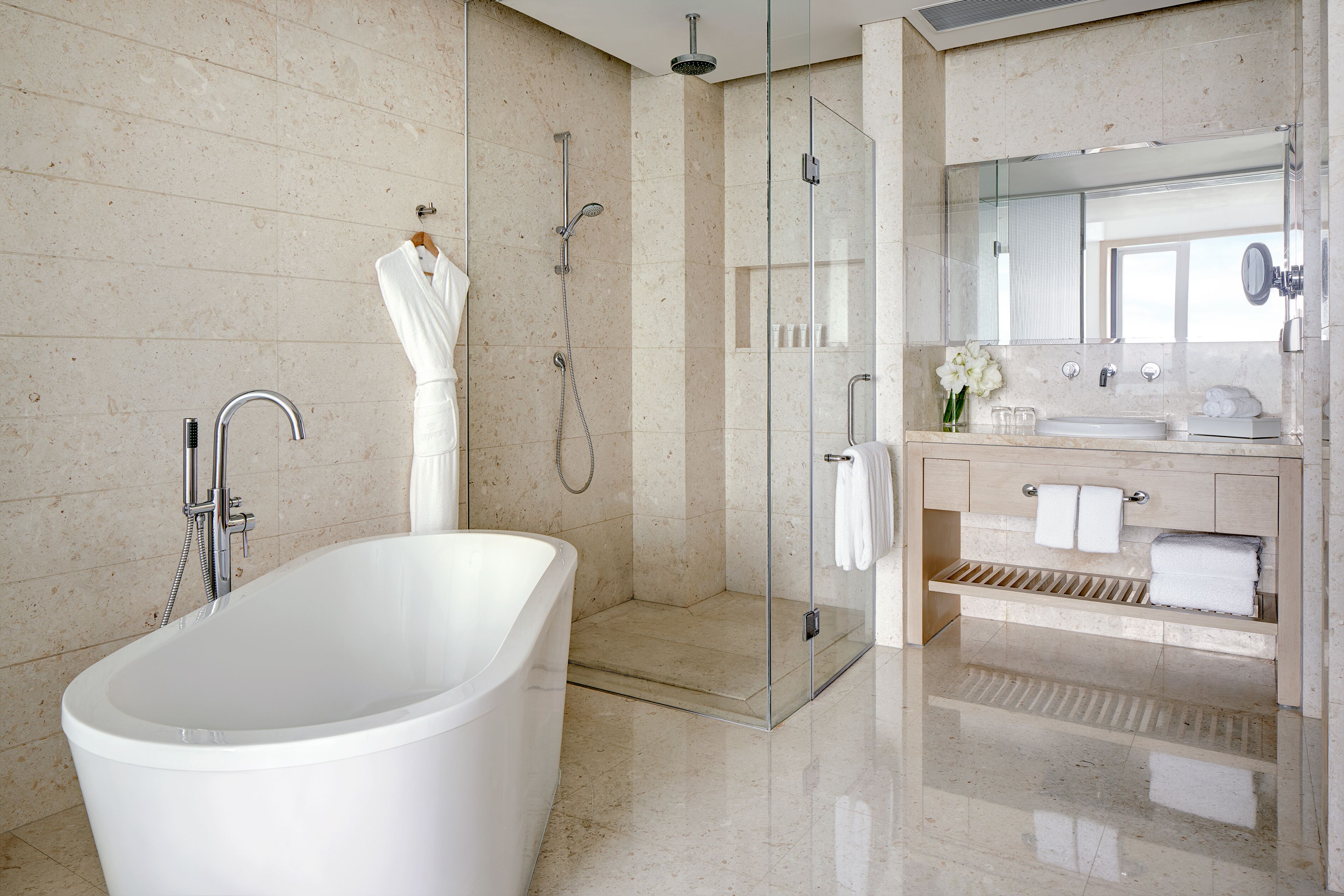 A modern bathroom with a freestanding bathtub, a glass-enclosed shower, and a vanity with a mirror and towel rack.