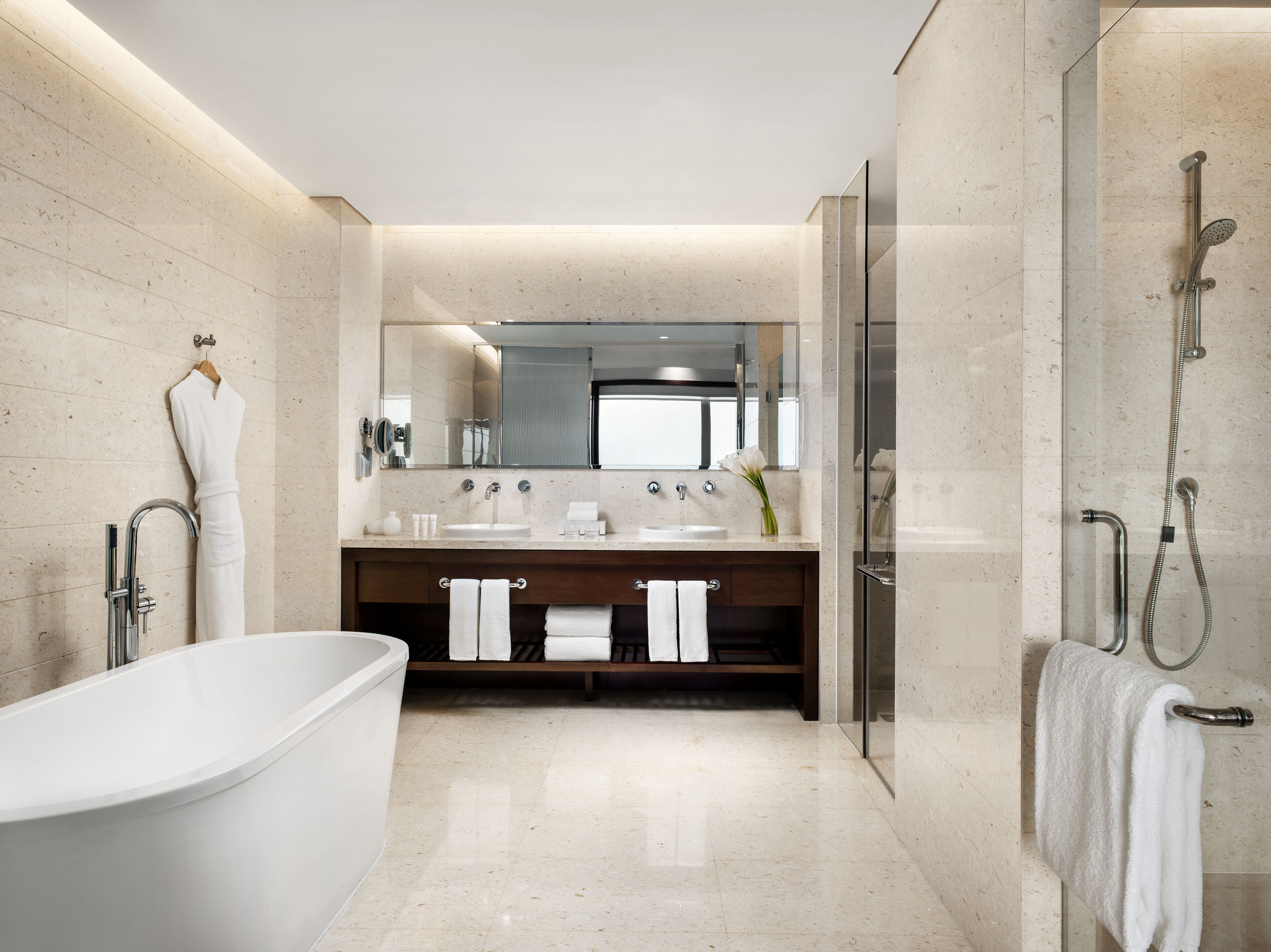 A modern bathroom with a freestanding bathtub, a double sink vanity, and a glass-enclosed shower area.