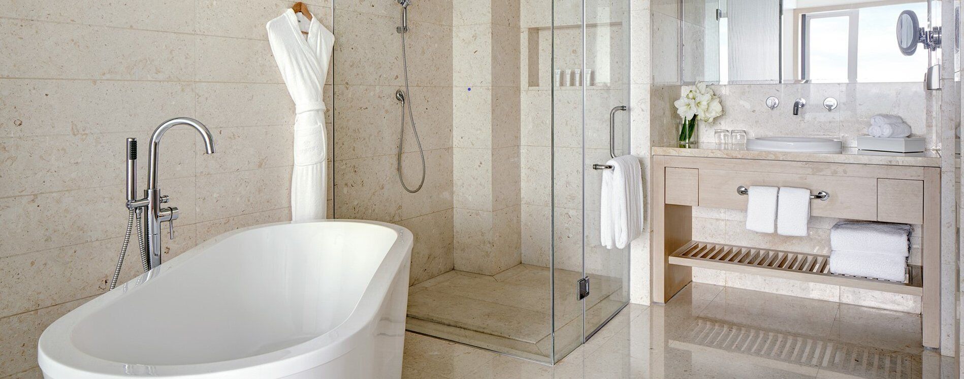 A modern bathroom with a freestanding bathtub, a glass-enclosed shower, and a vanity with a mirror.