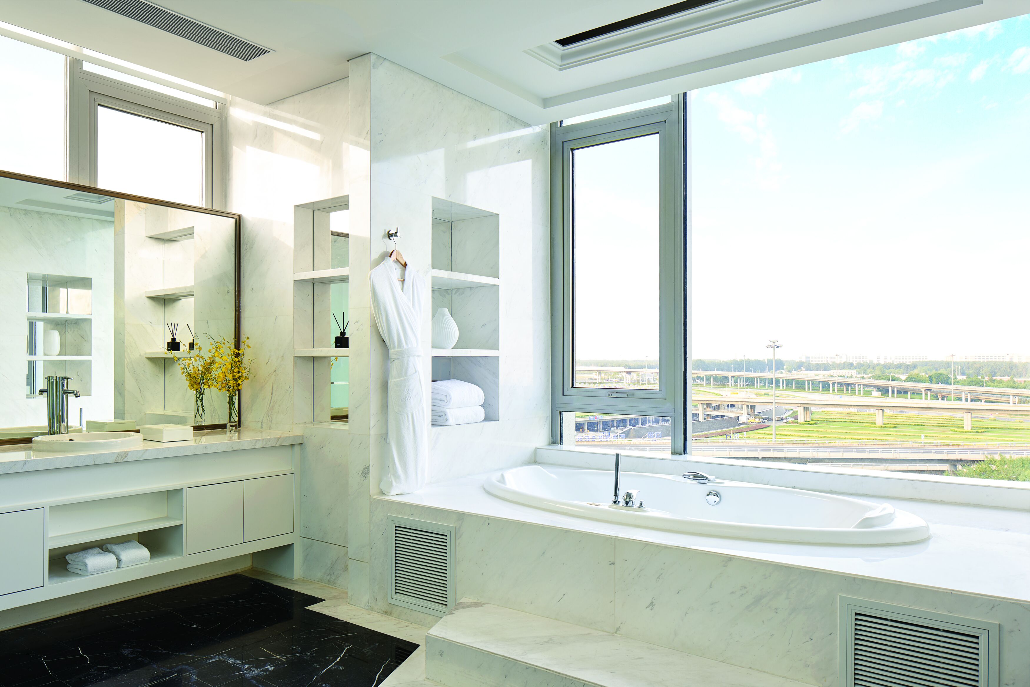 Een moderne badkamer met een groot raam, een badkuip en een wastafel met spiegel.