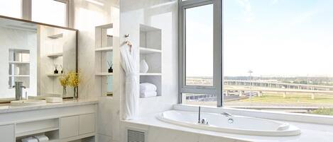 A modern bathroom with a large window, a bathtub, and a vanity with a mirror.