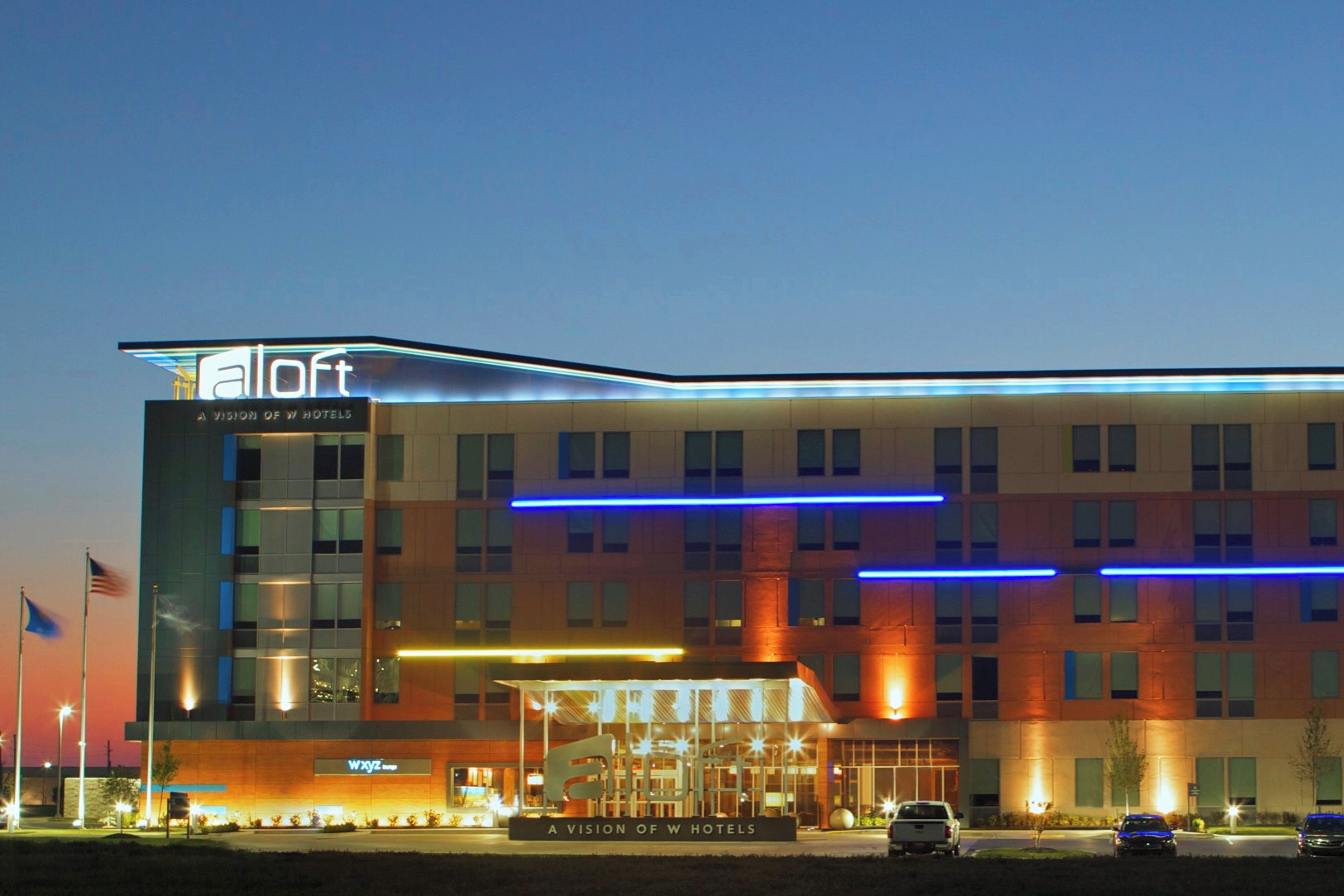 A modern hotel with a flat roof, multiple floors, and a prominent entrance with a ramp.