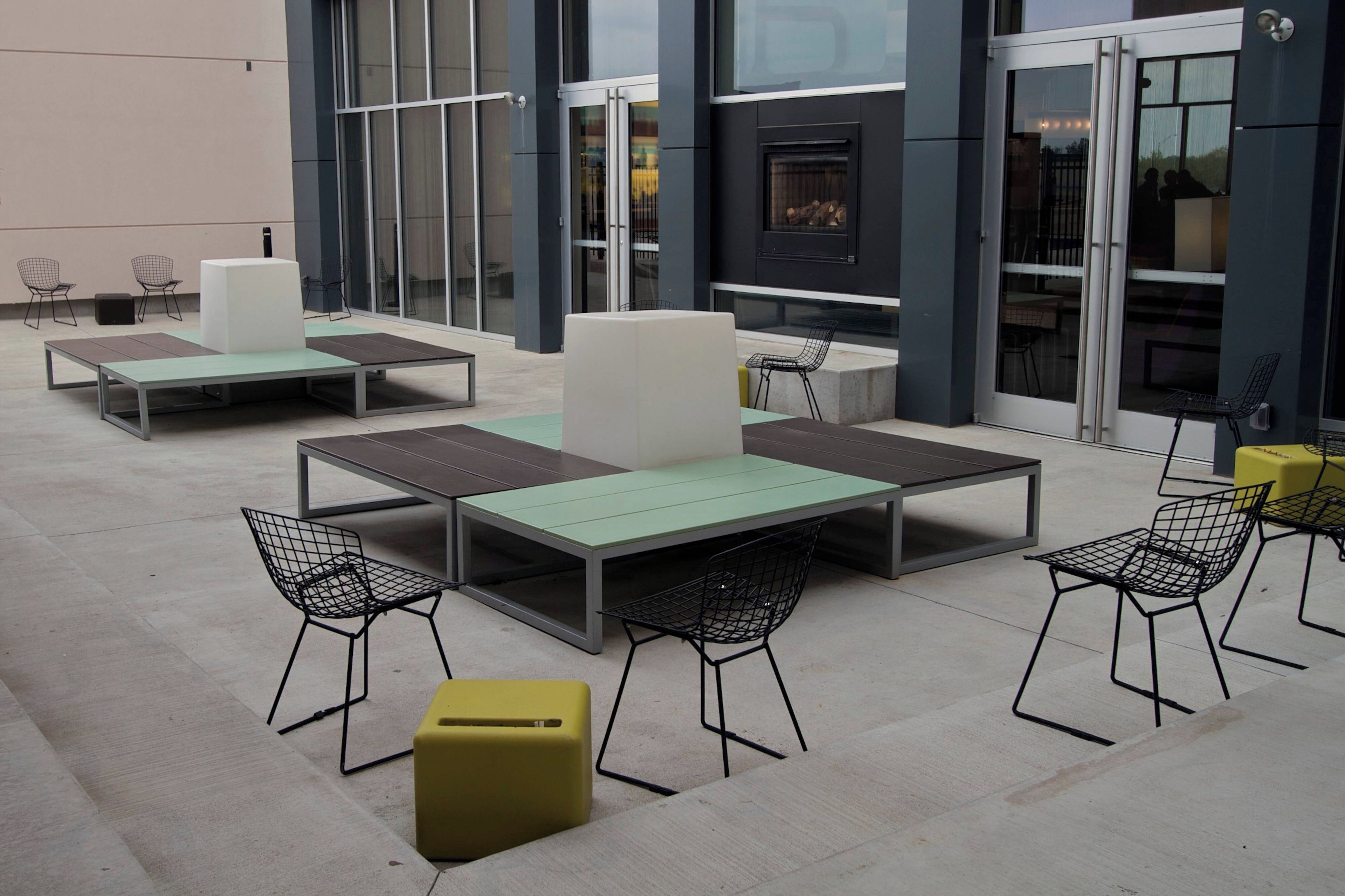 An outdoor seating area with tables and chairs, a fireplace, and a glass door entrance.