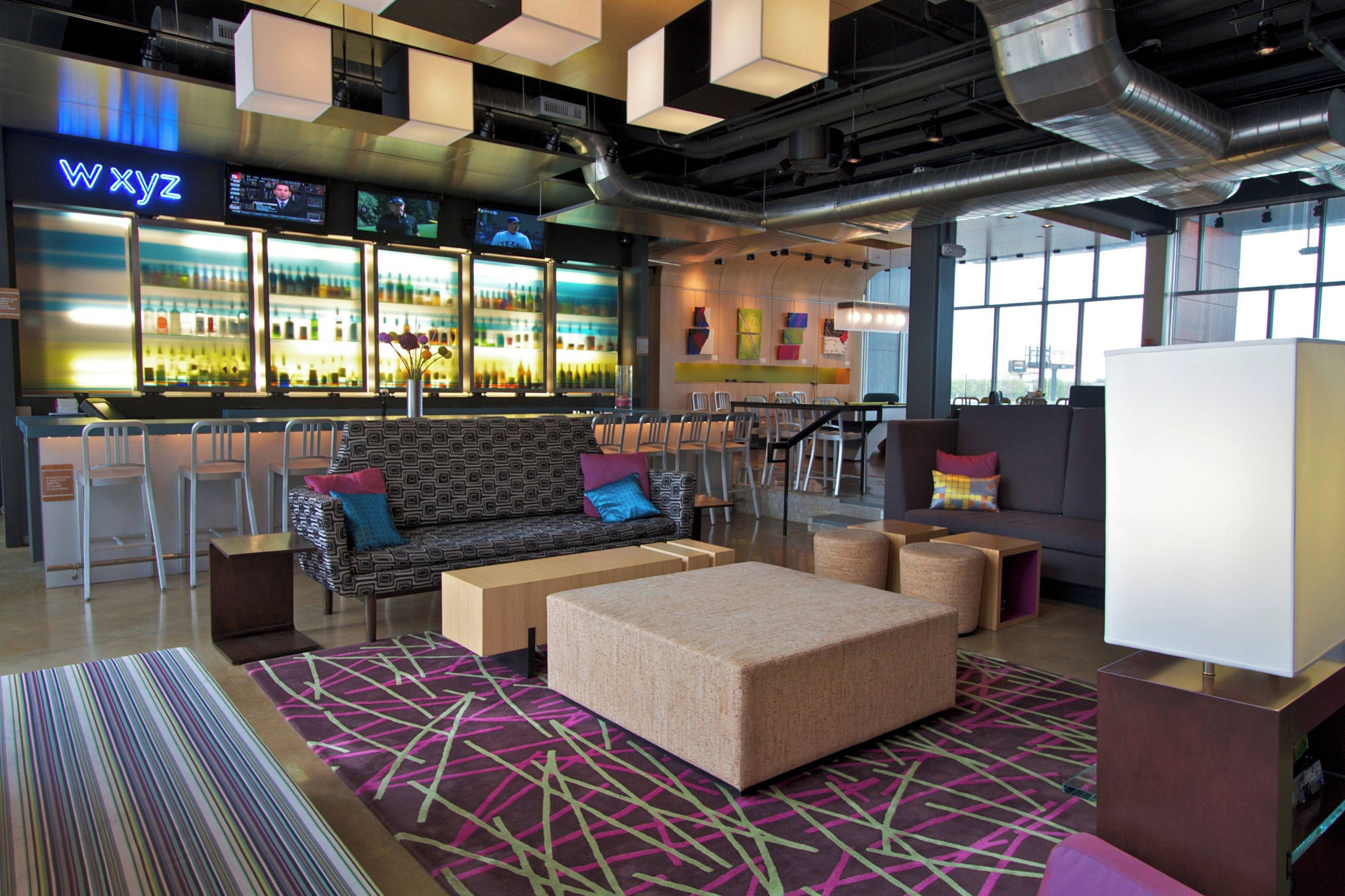 A modern bar area with a sofa and chairs, a patterned rug, and a large whiteboard.