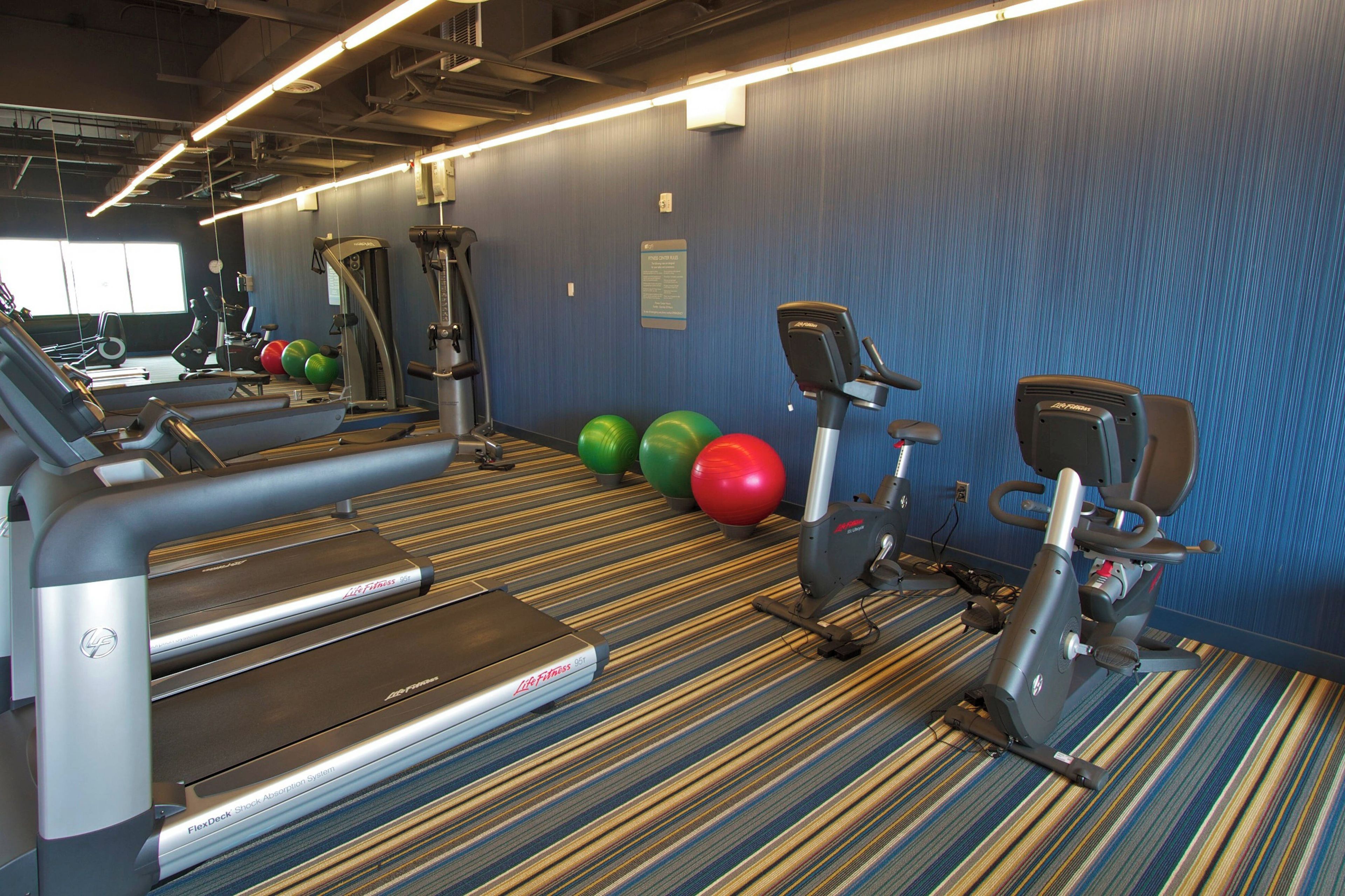 A gym with treadmills, elliptical machines, and exercise balls.