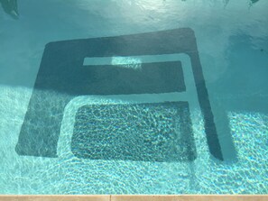 A swimming pool with a rectangular sunbathing area.
