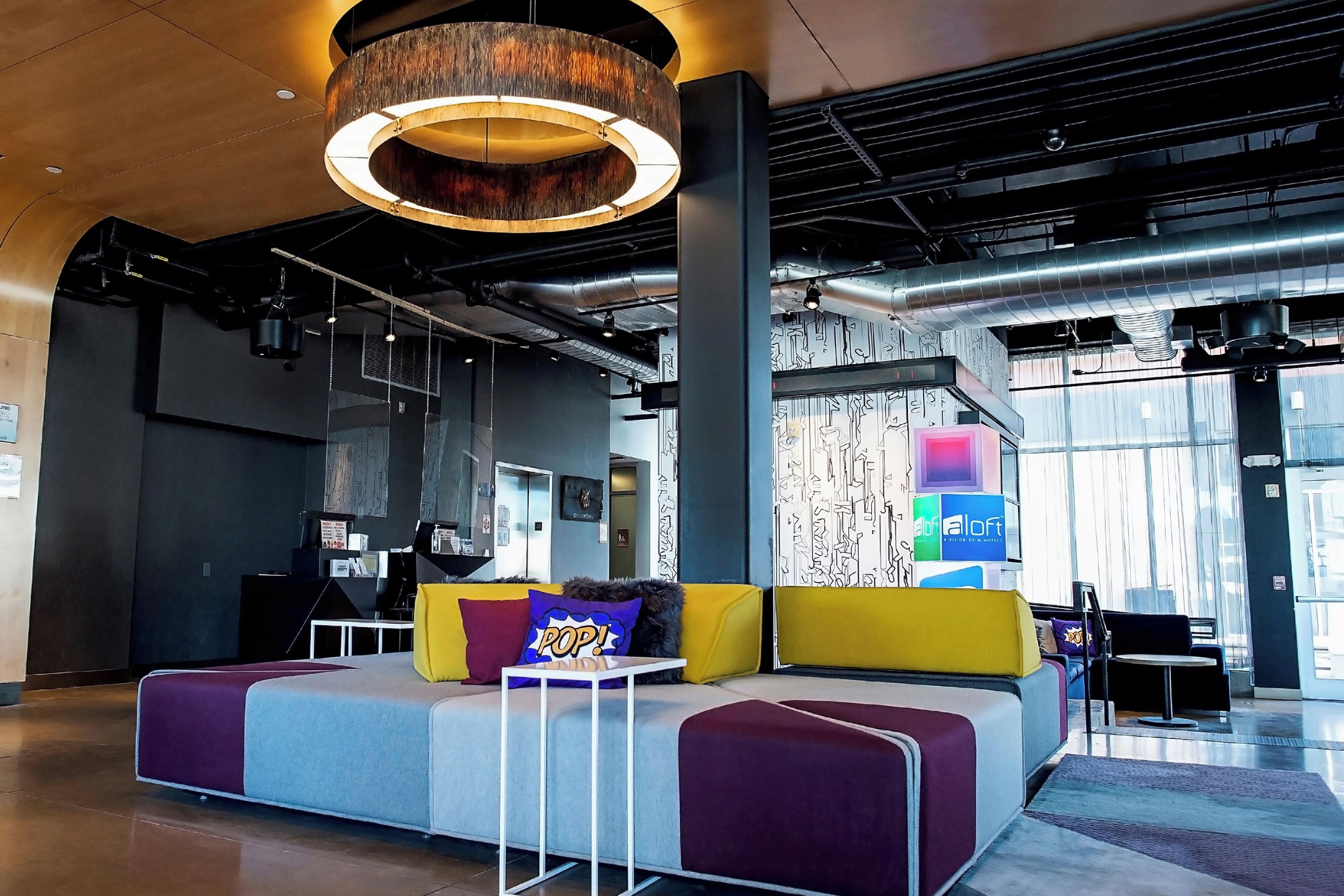 A modern lounge area with a sofa, a coffee table, and a hanging light fixture.