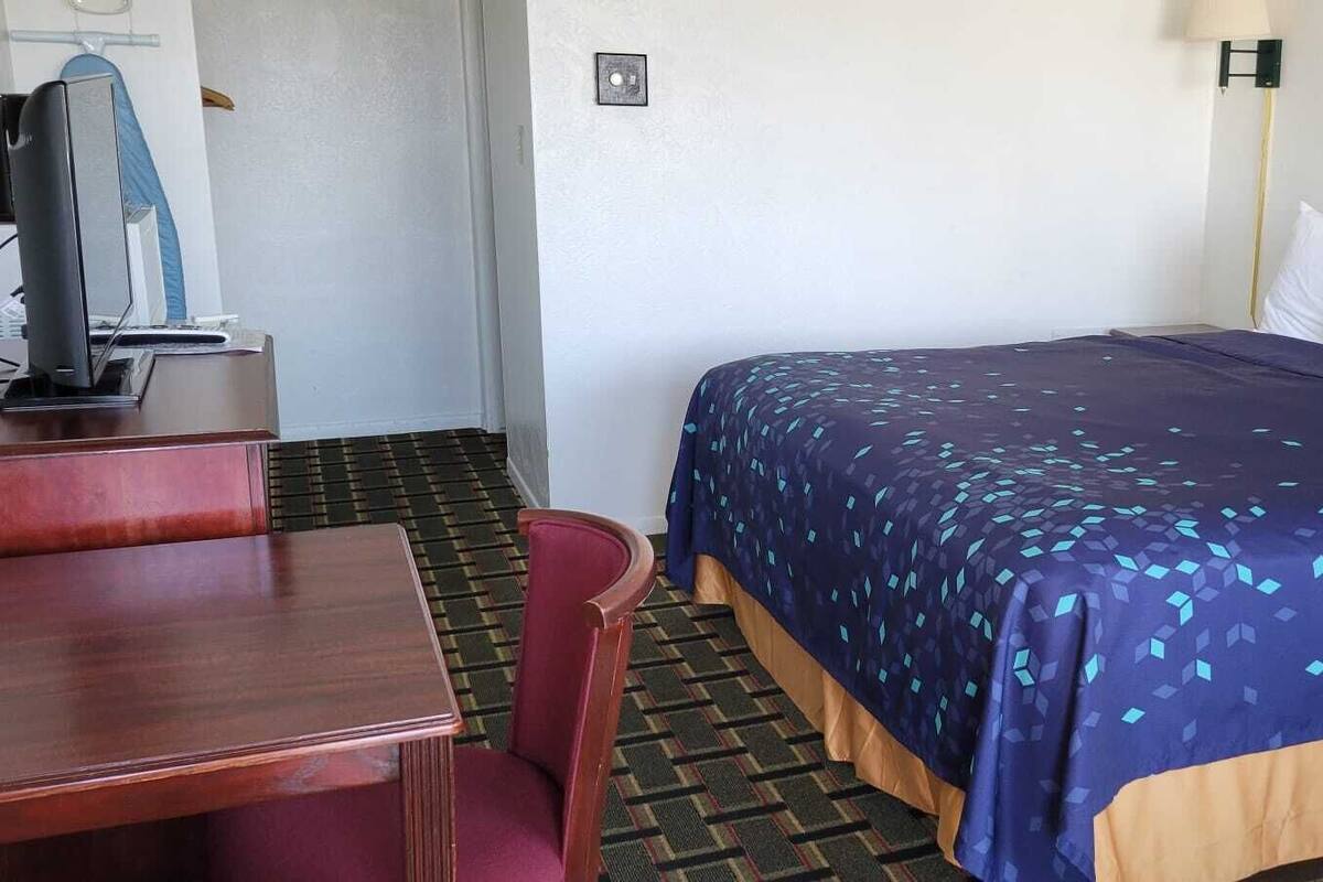 Une chambre d’hôtel avec un lit, un bureau et une chaise.