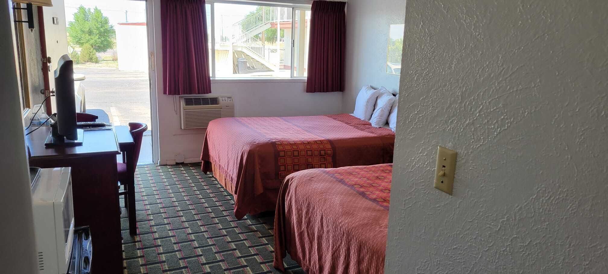Ett hotellrum med två sängar, ett skrivbord med en dator och en luftkonditioneringsanläggning.