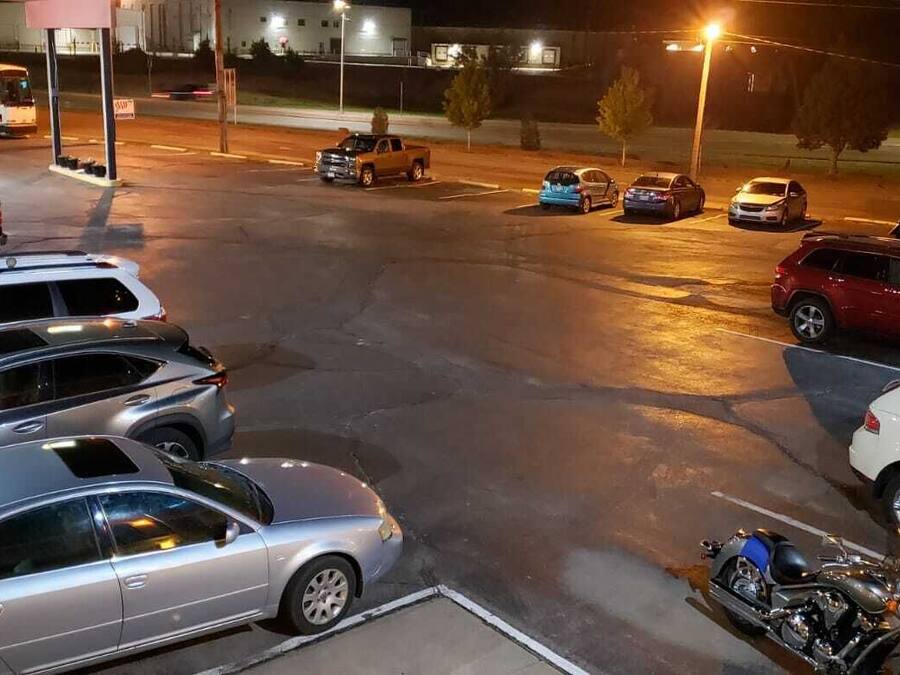 Un parking la nuit, avec différentes voitures et une moto.