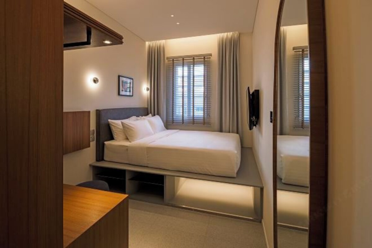 A modern bedroom with a bed, bedside tables, and a large mirror.