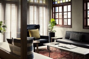 A modern living room with a sofa, armchair, coffee table, and a large window with blinds. - Wanderlust by The Unlimited Collection (Singapore)