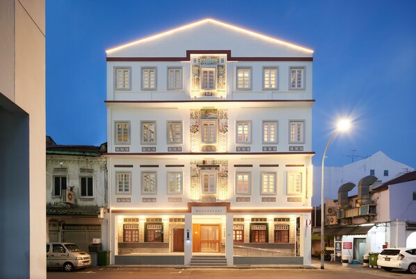Un hôtel à plusieurs étages doté d’une entrée principale, de balcons et d’une façade bien éclairée.