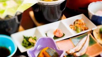 A variety of dishes on a table, including a bowl of soup, a plate with a rolled item, and several small dishes with different food items.