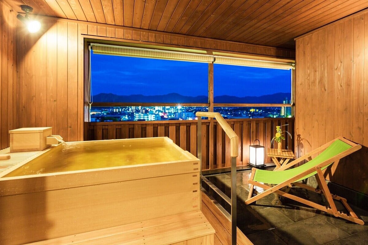 Un sauna en bois offrant une vue sur le paysage urbain au crépuscule.