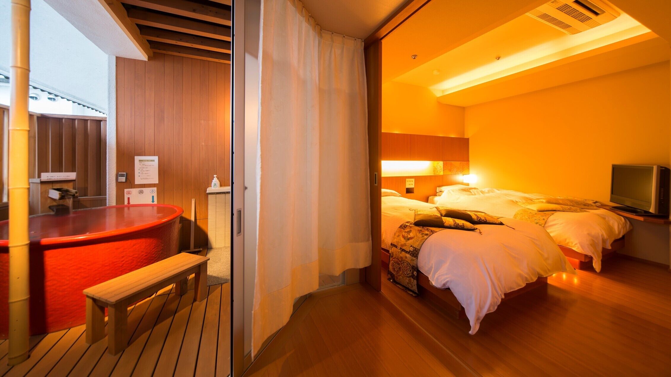 Una habitación de hotel con una cama, un televisor y un banco de madera.