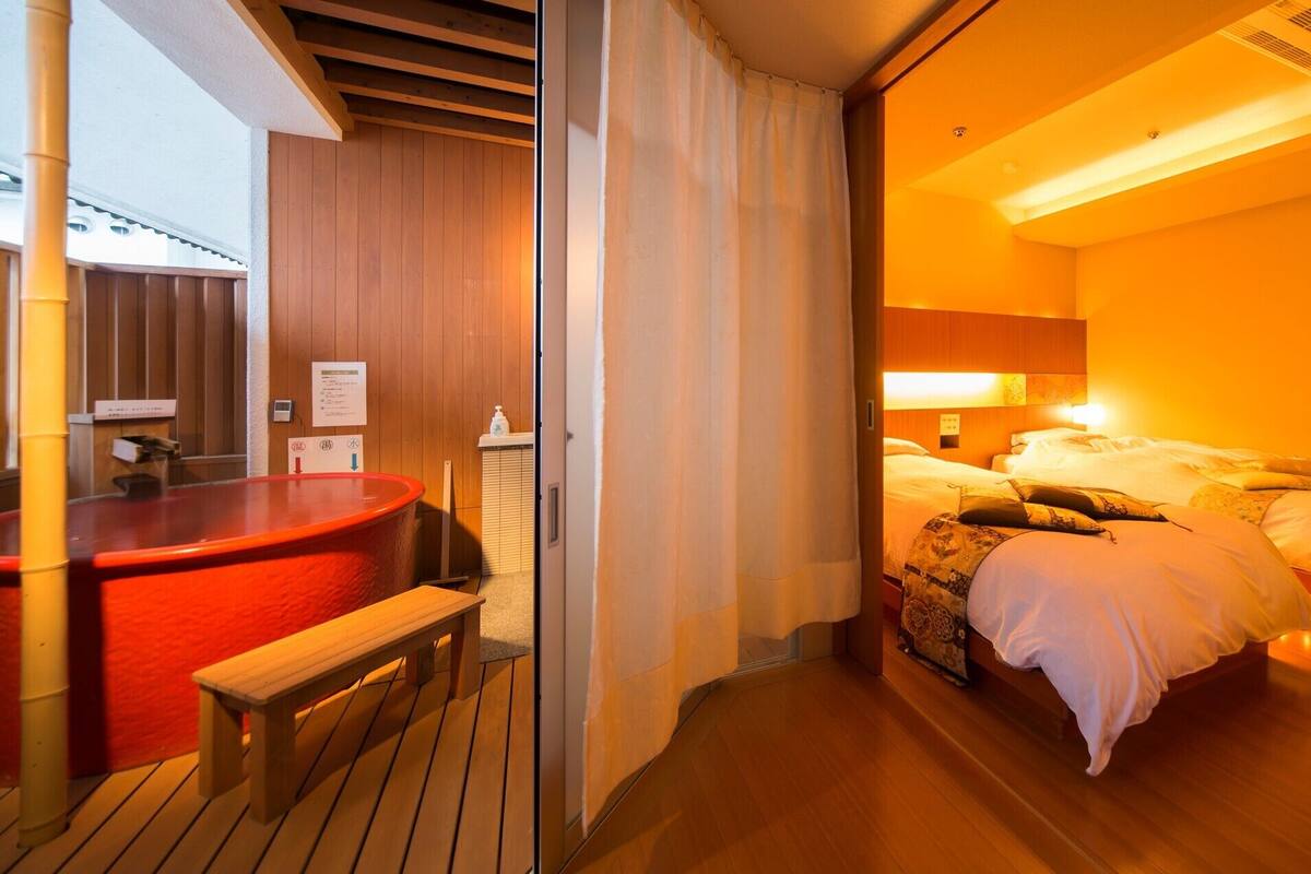 A hotel room with a bed, a TV, and a wooden bench.